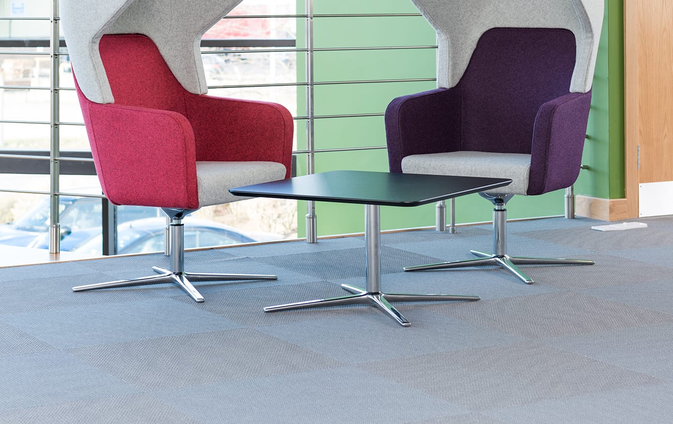 Two lounge chairs with offices and a table in a room.